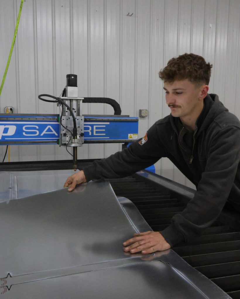 Employee bending metal ductwork at Western Edge Metals shop in Spearfish, SD for HVAC fabrication.